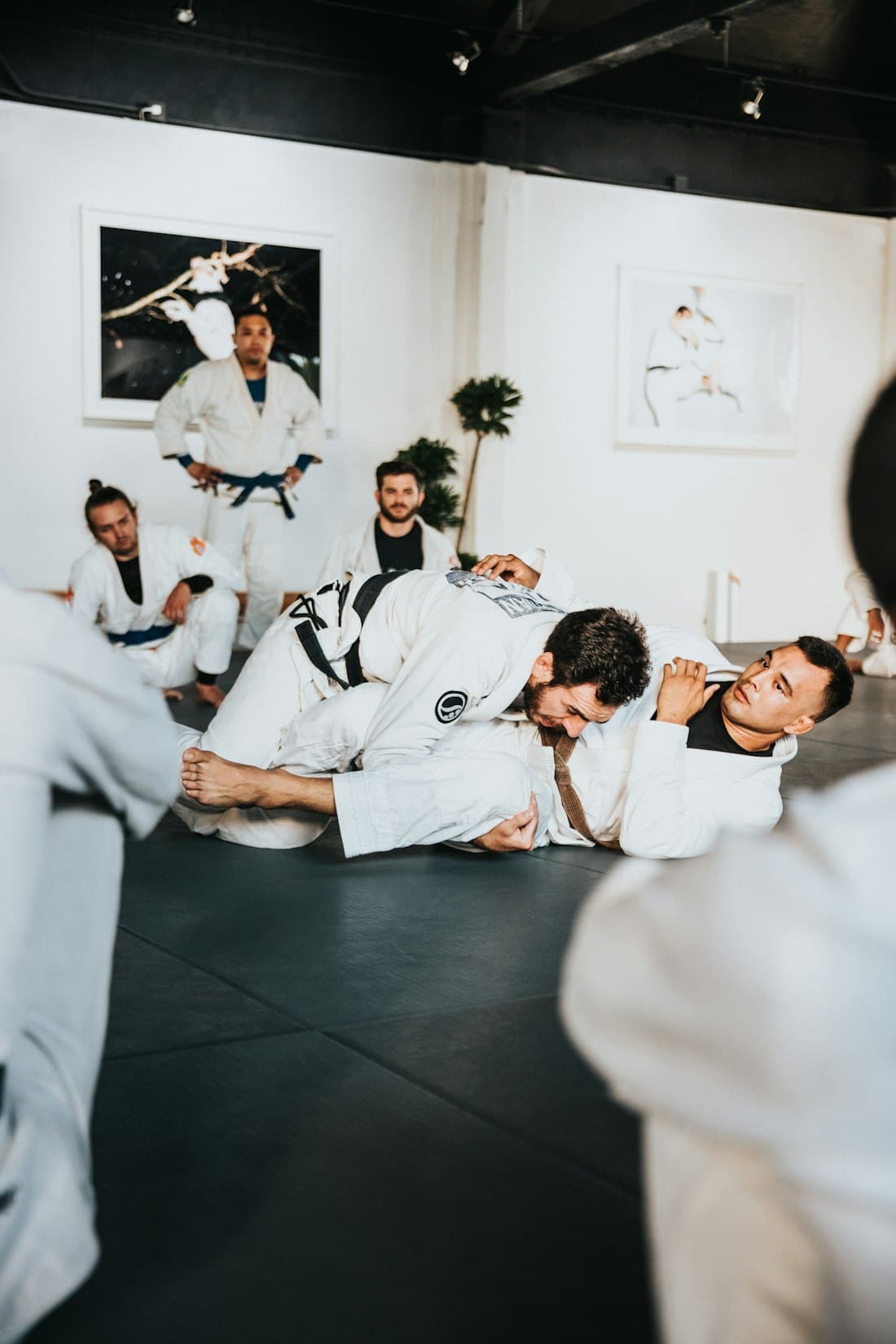 Martial arts class in white gis practising on the mat with their instructor