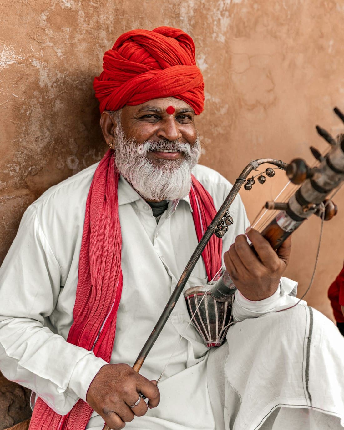 Indian musician in a red turban playing a stringed instrument
